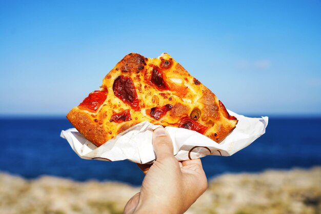 _2023-11-27_13_48_focaccia-barese-slice-with-mediterranean-sea-background-focaccia-pugliese-against-blue-sea-sky-baristyle-focaccia-bread_63239-4464.jpg